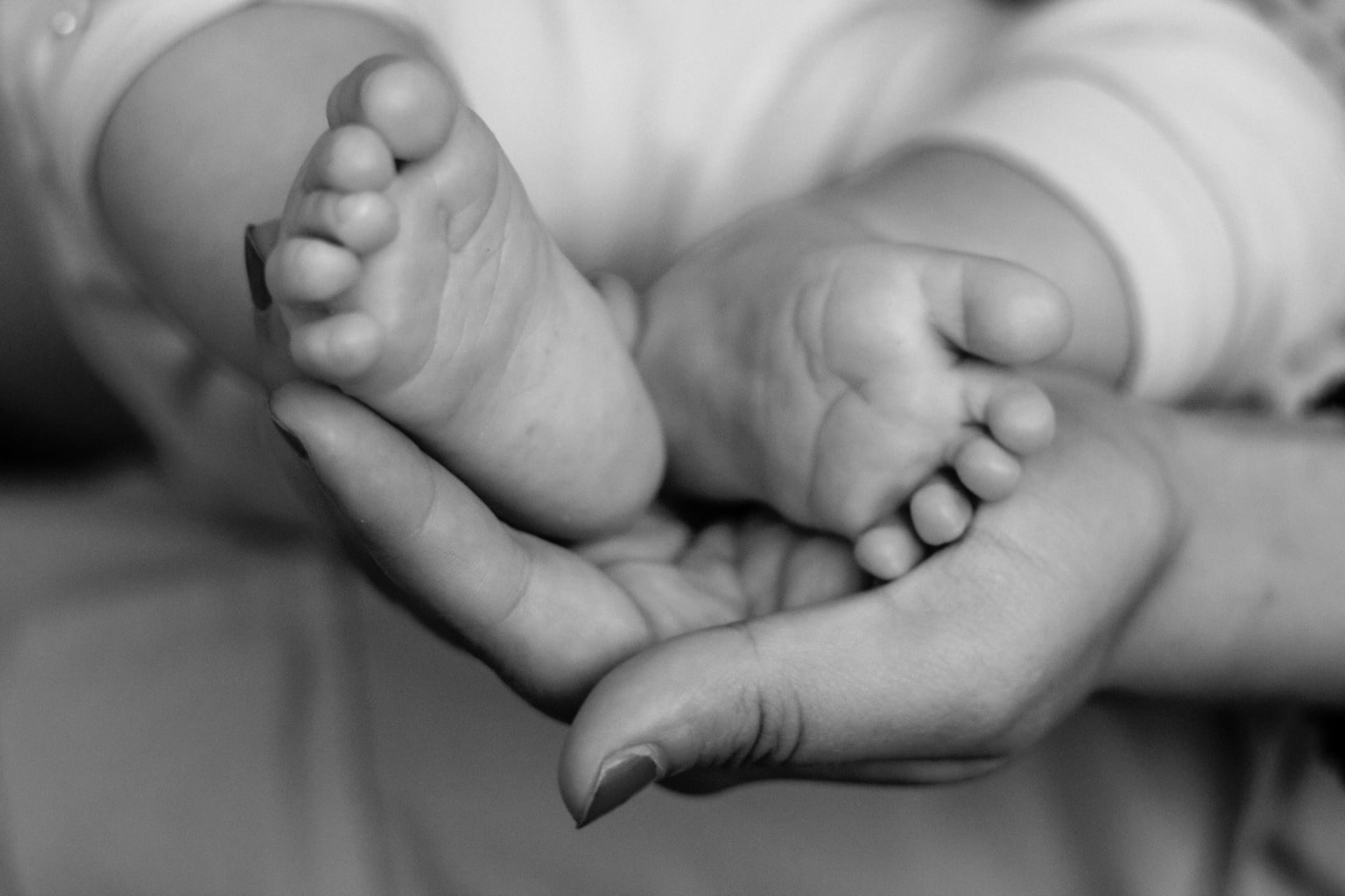 Newborn's feet cradled in mother's hands, postpartum care